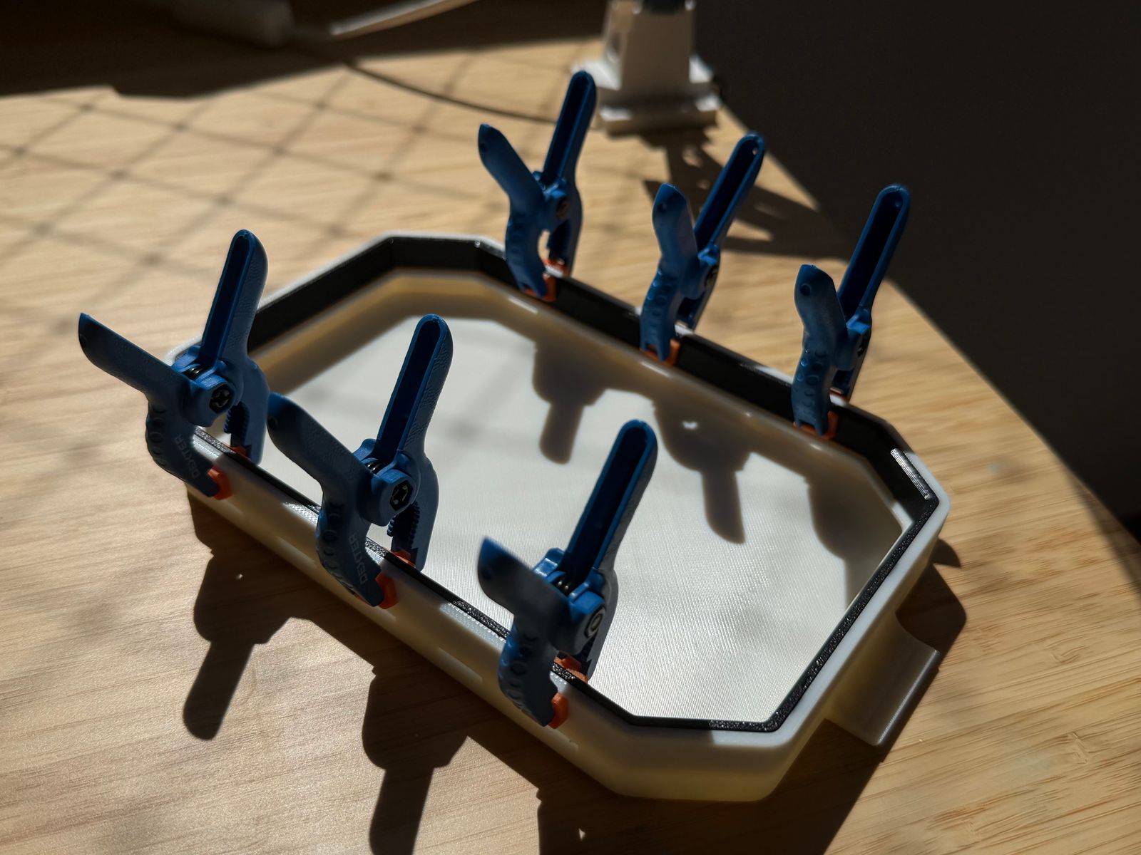 The TPU seal being glued into the ASA shell under seven spring clamps while the adhesive cures.