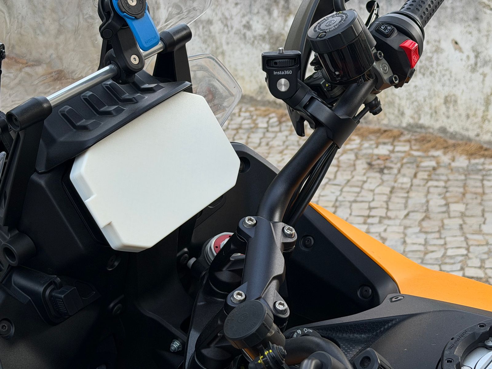 The Moto Guzzi Stelvio cockpit with the white dash cover in place over the TFT screen, parked on a cobbled street in Cascais.
