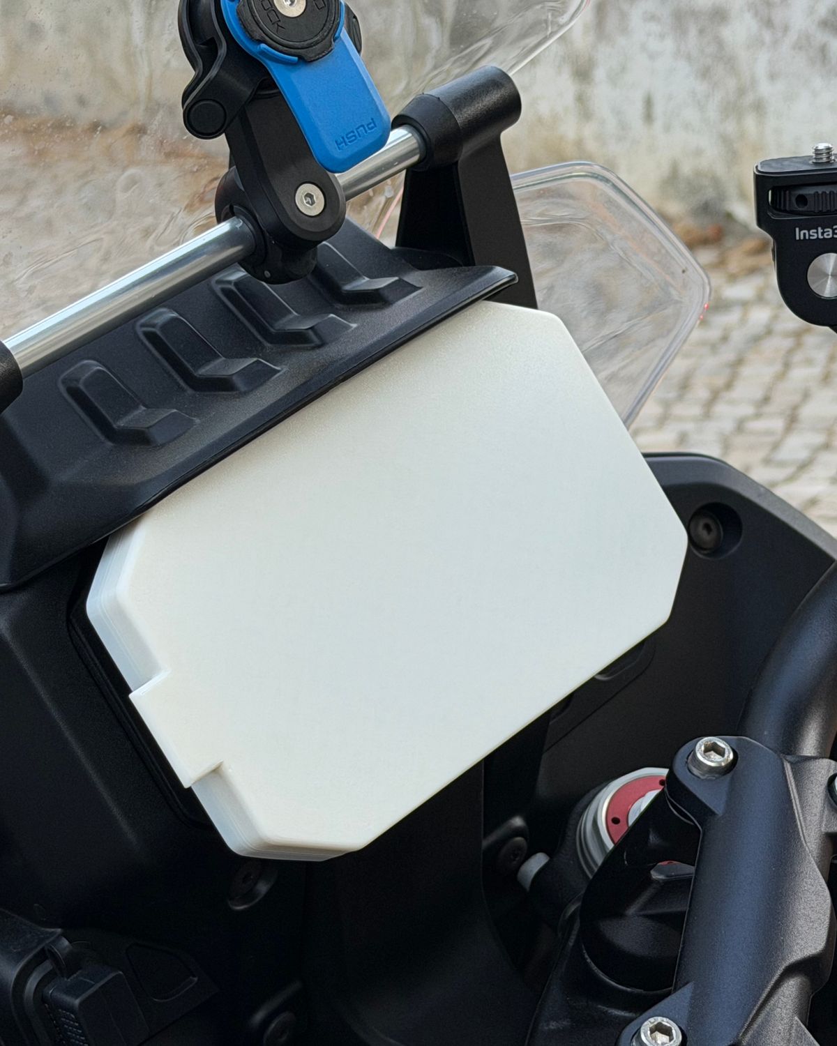 White 3D-printed dash cover fitted over the TFT instrument screen of a Moto Guzzi Stelvio motorcycle in Cascais.