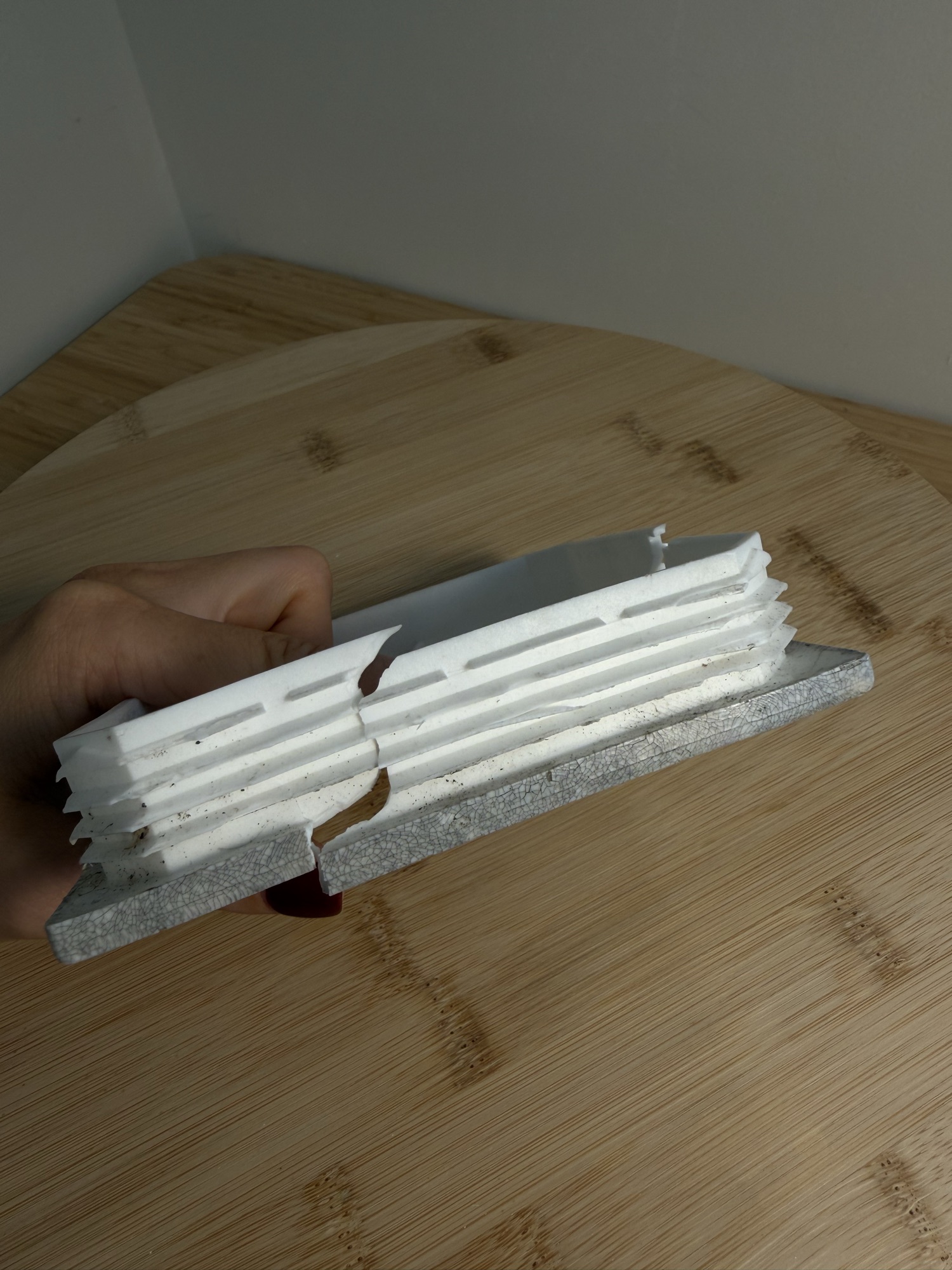 The original cap held in a hand, split through its side, showing the moulded fins that gripped the post.