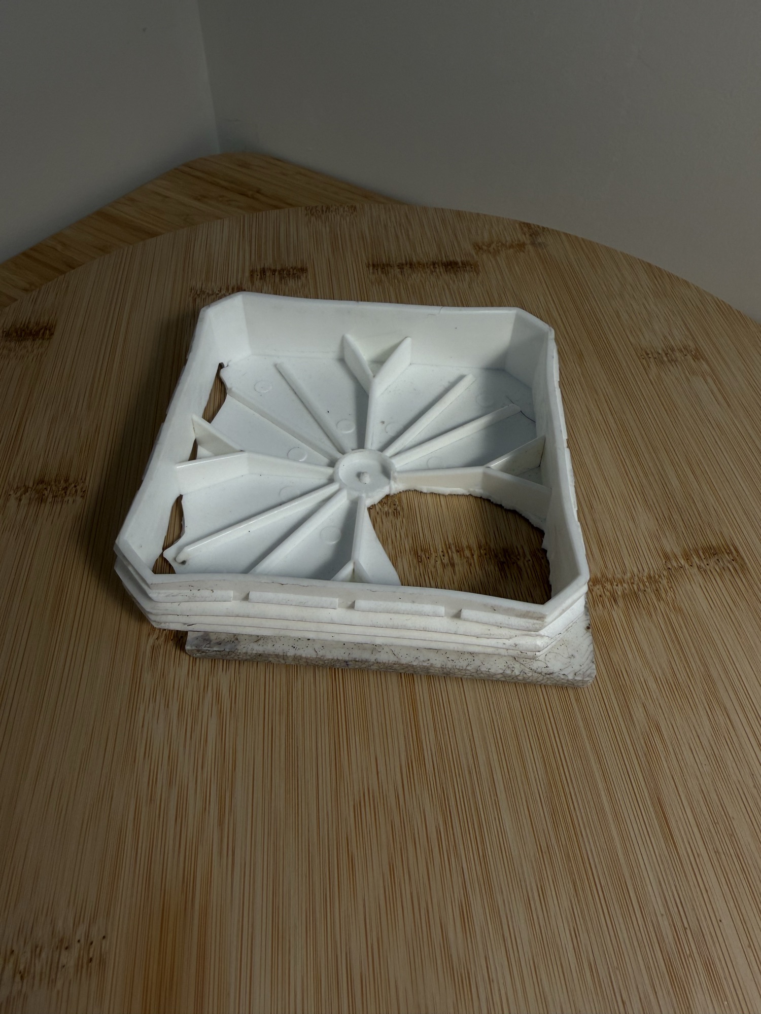 The surviving original cap, white moulded plastic, with a large hole broken through the top and its radial ribs exposed.