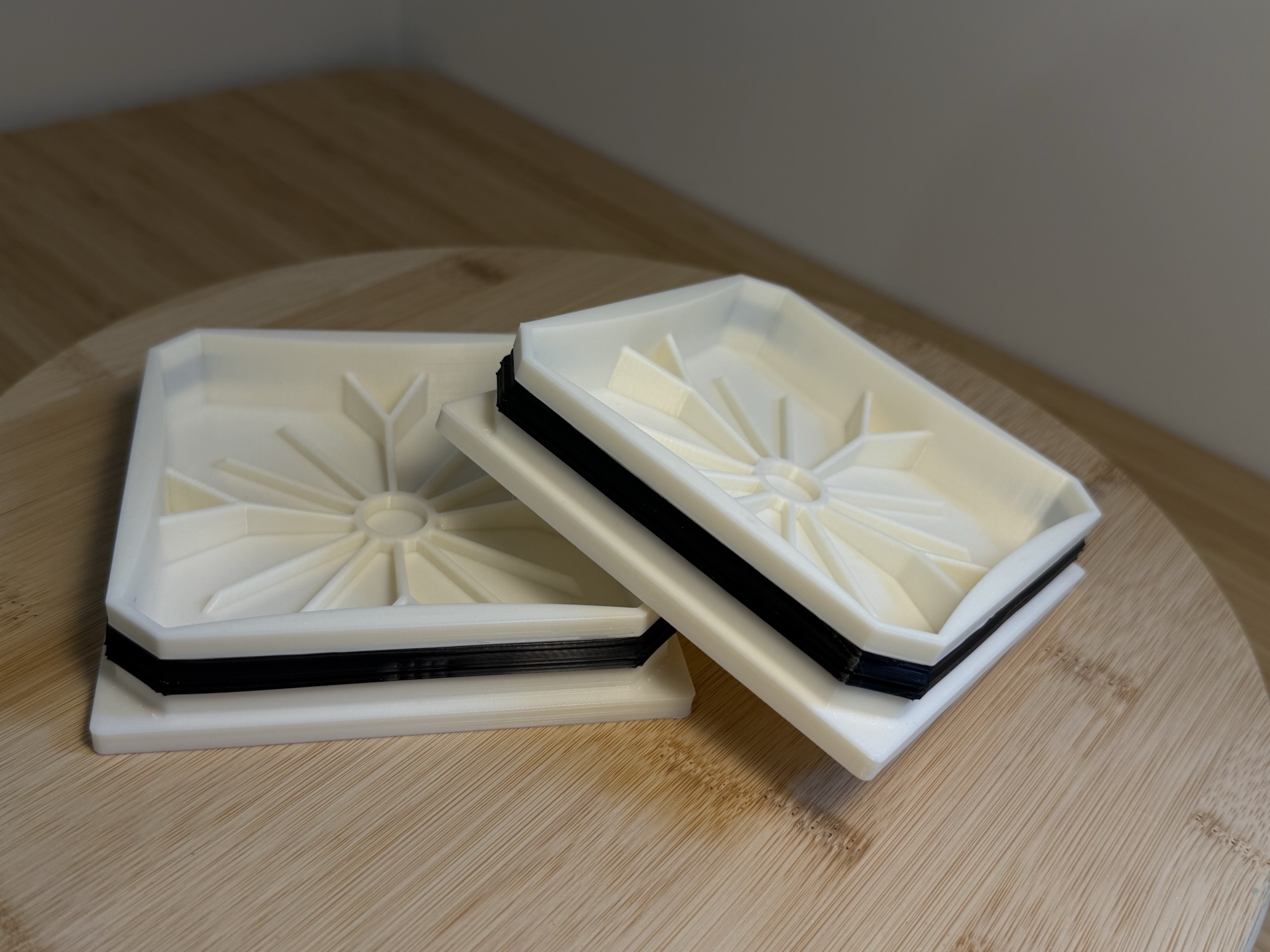 The two new 3D-printed caps in white ASA, each with a black TPU seal, side by side on a wooden board.
